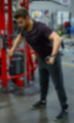 A man leans forwards while using a cable machine in a gym to perform forward-leaning cable chest flys