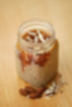 A mason jar full of overnight oats, seen with chopped almonds on top.