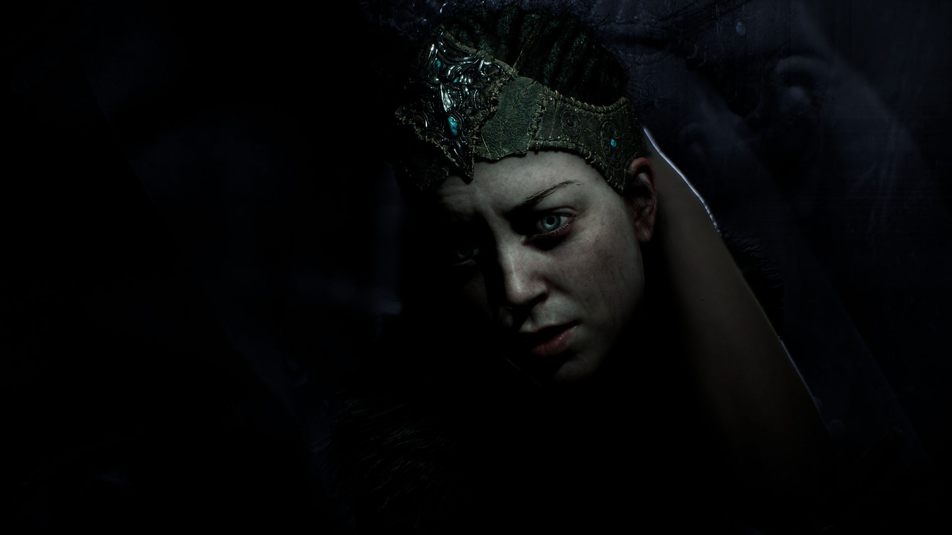 A close-up of Senua's face depicts a melancholy mood.
