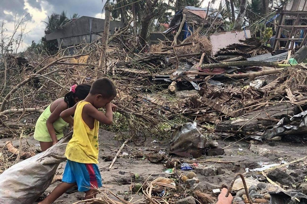 Young children walk near debris from a typhoon (Photo: © UNICEF Philippines/Ruel Saldico)