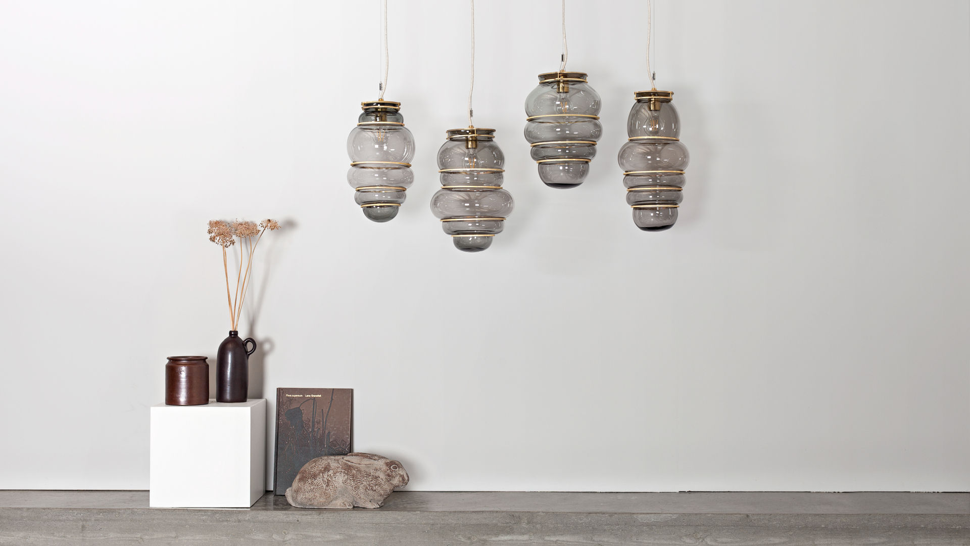 Hand-blown glass pendant lamps by Stoft Studio with brass details, showcasing Scandinavian lighting design in a minimalist interior setting.