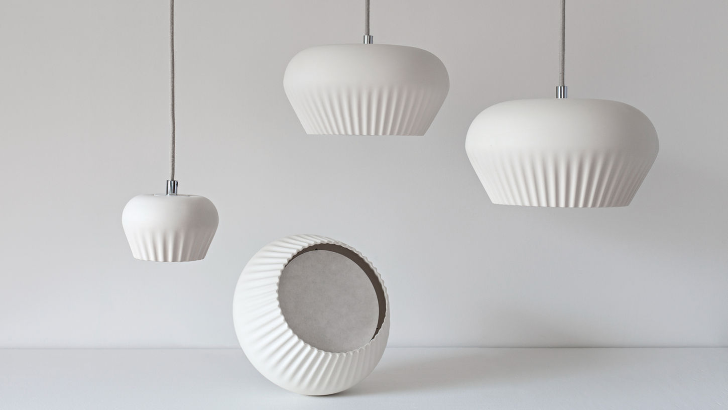 White ceramic lamps by Stoft Studio with ribbed surfaces and sculptural forms, reflecting Scandinavian lighting design and minimal elegance.