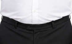 白い背景に、白いシャツと黒いパンツの男性が正面を向いて立ち、穏やかにほほ笑んでいる。