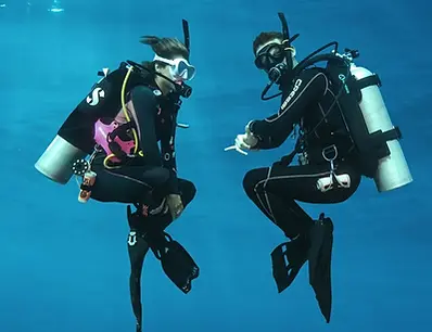 PADI Master Scuba Diver training in Cancun – two divers practicing buoyancy control in cross-legged position underwater