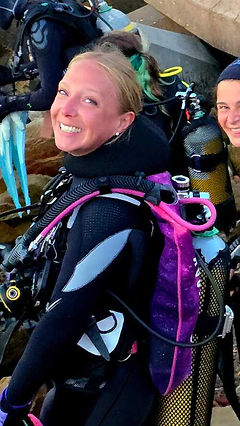 Diver adjusting a hood while discussing comfort notes with an instructor at a cenote.