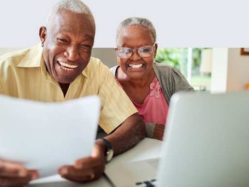 Couple smiling reading documents with laptop open