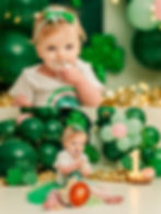 Lucky One cake smash, first birthday photos, cake smash photography, shamrock theme, green and pink decor, twinkle lights backdrop, birthday milestone session, toddler photo session, baby girl cake smash, themed cake smash, fun cake smash ideas, studio cake smash, first birthday celebration, lucky one birthday theme, baby’s first cake, cake smash outfit, baby photography session, first birthday memories, custom cake smash, milestone photography
