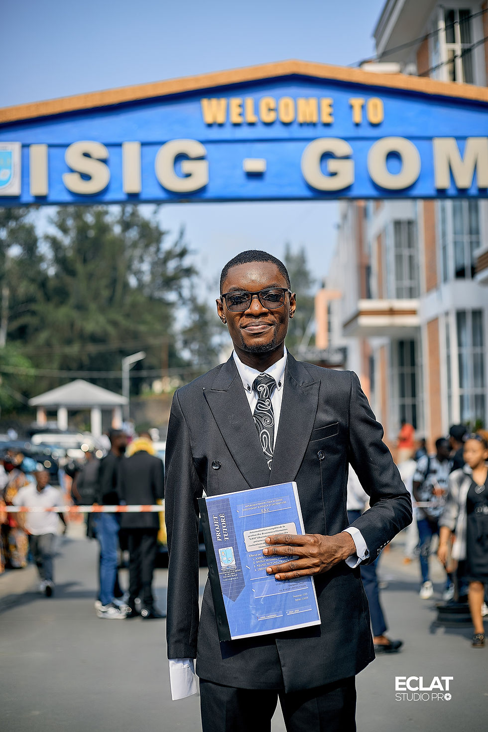 Ushindi posing for a photo in a suit after graduation