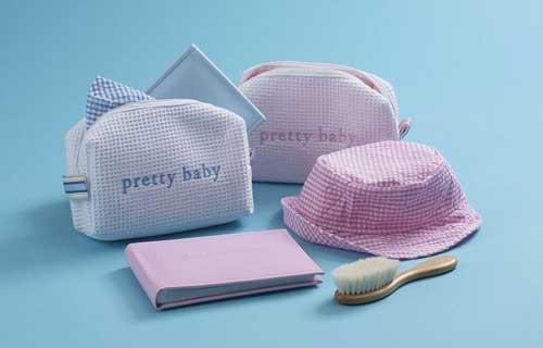 Gift set for baby in pink or blue includes a zippered pouch, photo album, hair brush and sun hat.