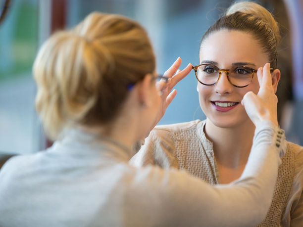 Une opticiene ajustant les lunettes d'une cliente