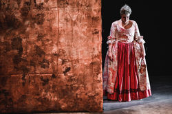 Melissa looking sad stood by a gold wallpaper