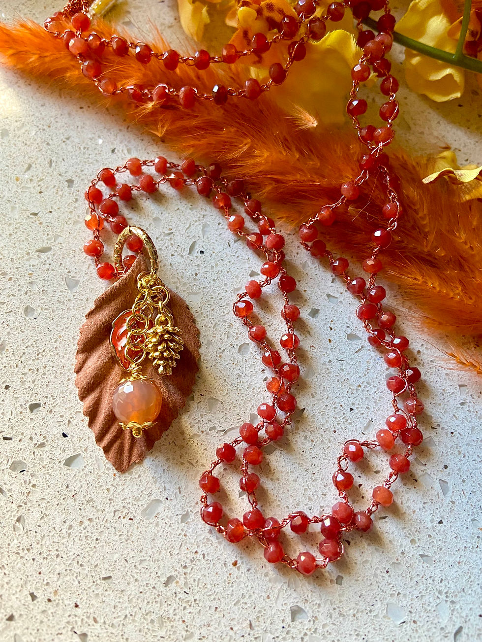 Collana lunga lavorata a mano all'uncinetto con filato prezioso, cristalli e ciondolo con foglia in tessuto rigido e pendenti con pietre dure, colore arancione