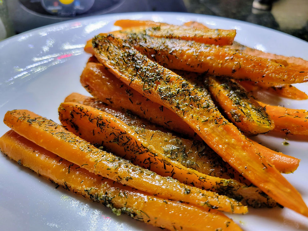 vibrant orange Roasted carrots seasoned with dill on a white plate.
