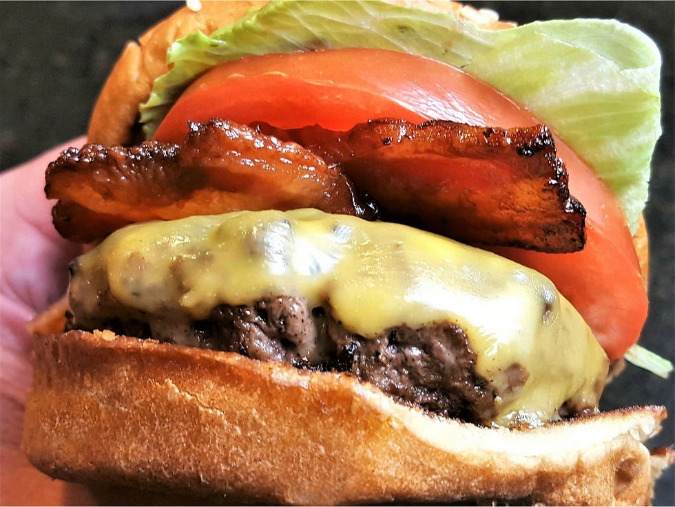 Close up photo of a cheeseburger with bacon, lettuce and tomato on a roll