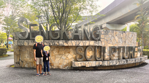 A man and a boy standing in front of the sign that says "Sengkang Sculpture Park".