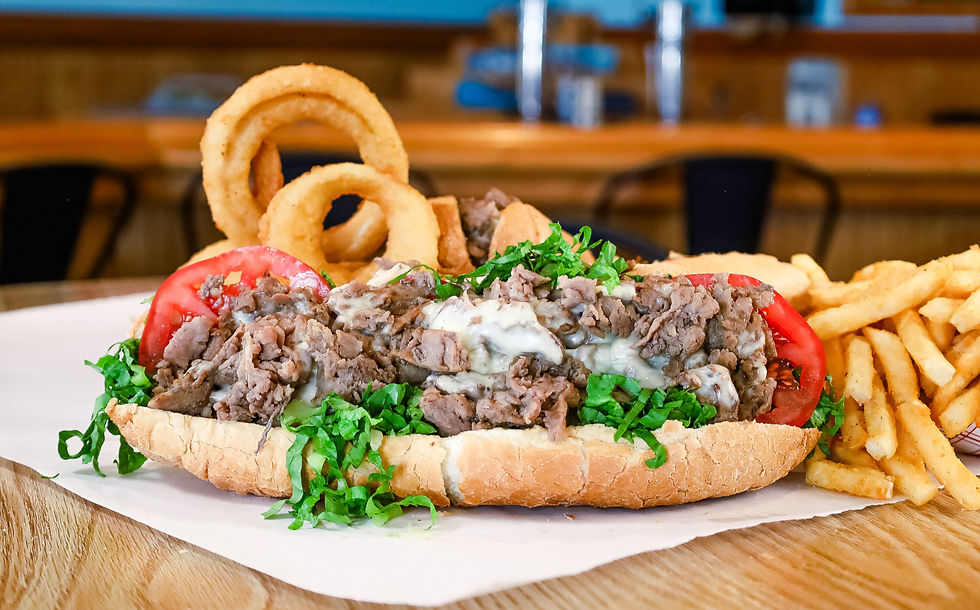 Philly steak sub with lettuce and tomato and onion rings