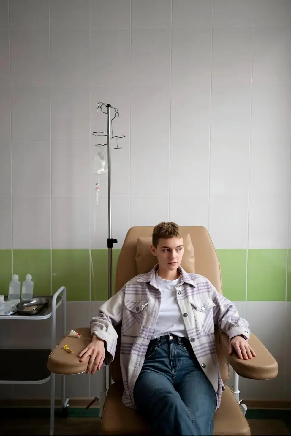 Person seated in a clinic chair with an IV drip