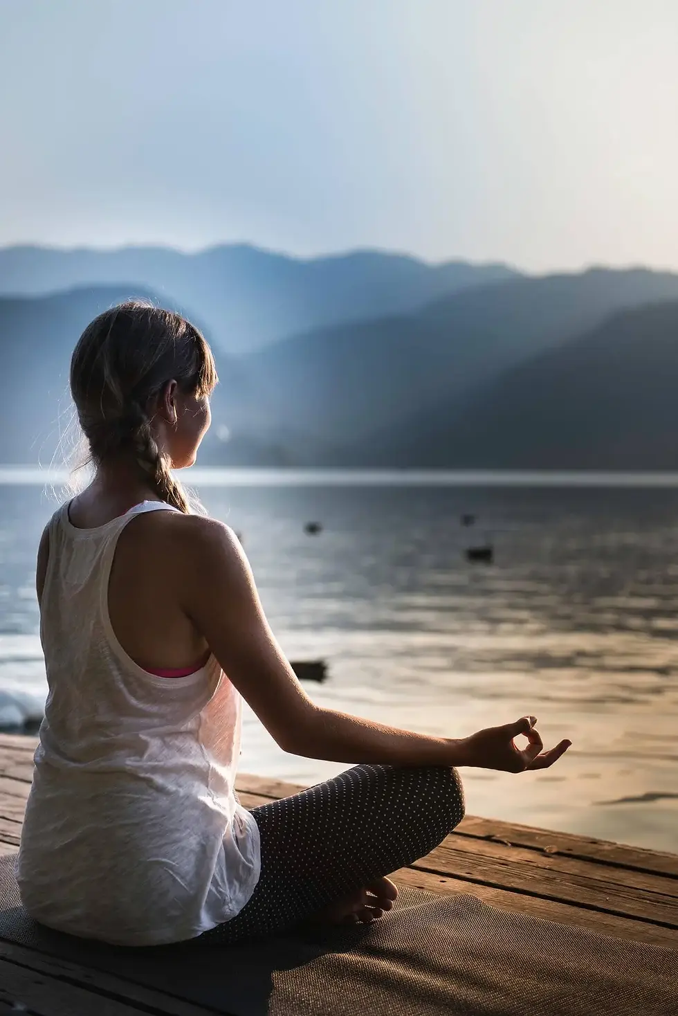 Person meditating cross-legged by a lake