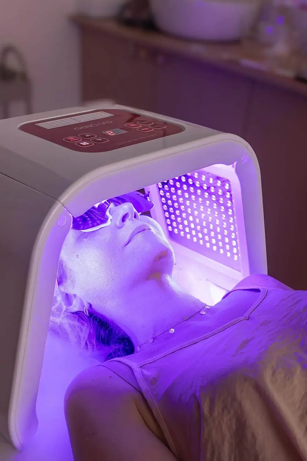 Person lying under an ultraviolet light therapy device
