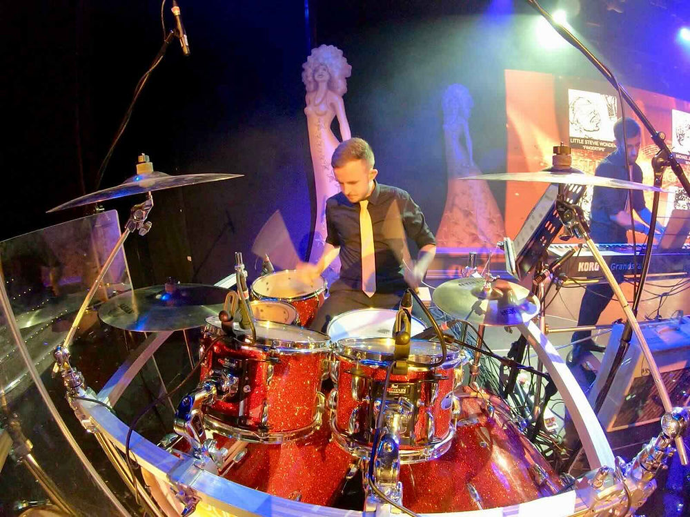 Drummer playing red drum kit on stage