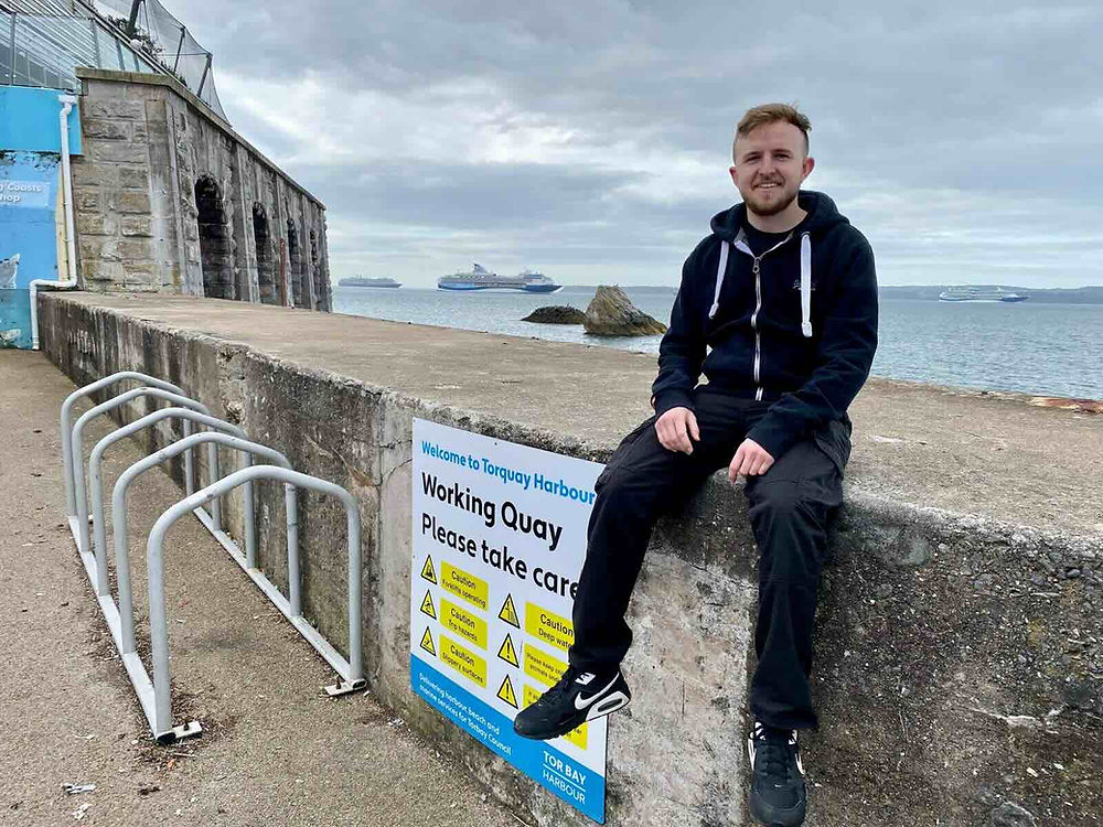 Drummer sitting on a wall at Torquay Harbour