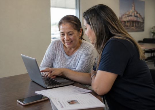A Community Health Worker assisting a woman improve her digital skills. 
