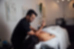 Person relaxing in a minimalist wellness studio with soft ambient lighting and organic textures
