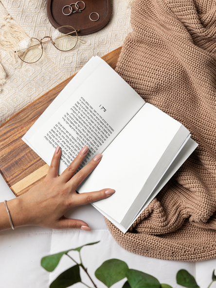 mockup-featuring-a-woman-s-hand-holding-an-open-book-in-a-cozy-bed-m58546