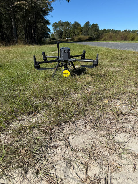 A survey drone with a sensor payload on the ground in grass before flight
