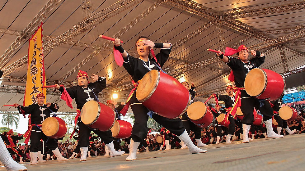 Performers ,clad in traditional black outfits with white details and trimmings and with taiko drums on them, point with a drumstick as they dance the Eisa, a traditional Okinawan dance performed for occasions such as Obon.