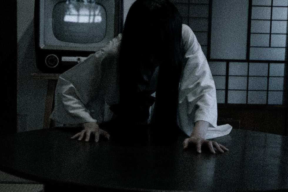 A ghost in a white dress with long black hair in a Japanese-style room with sliding doors and an old-school television set behind her