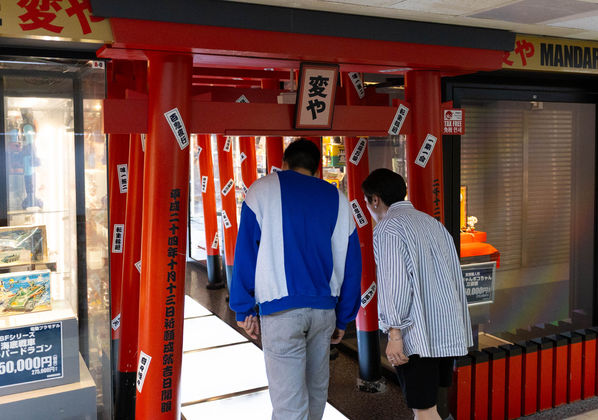 2 friends exploring Nakano area and bowing at the entrance of a traditional Tori door