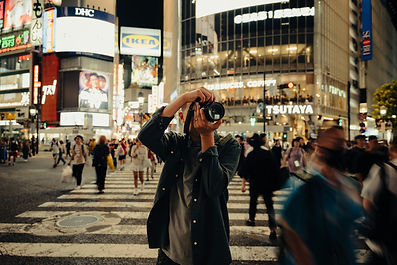 A person taking a picture with a camera in a busy street in Tokyo, Japan