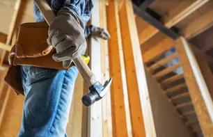 A close up of a worker holding a hammer in a home under construction.