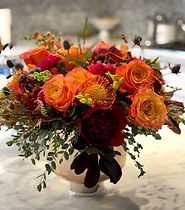 orange and red floral centerpiece arrangement with roses and pincushion flowerson offer with floral subscription for home