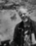 Monochrome photograph of filmmaker Christopher Doyle smiling and squinting while holding a camera.