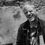 Thumbnail: Monochrome photograph of filmmaker Christopher Doyle smiling and squinting while holding a camera.