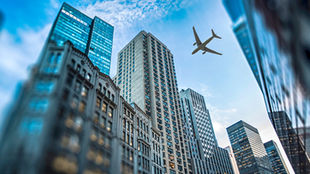 A plane flies over skyscrapers
