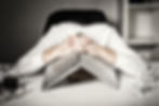 A man hiding his head under his laptop
