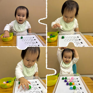 A toddler plays a counting game with colorful pom-poms, learning while having fun.