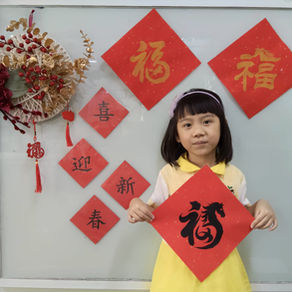 A child holding a red “Fu” sign for Lunar New Year celebration.
