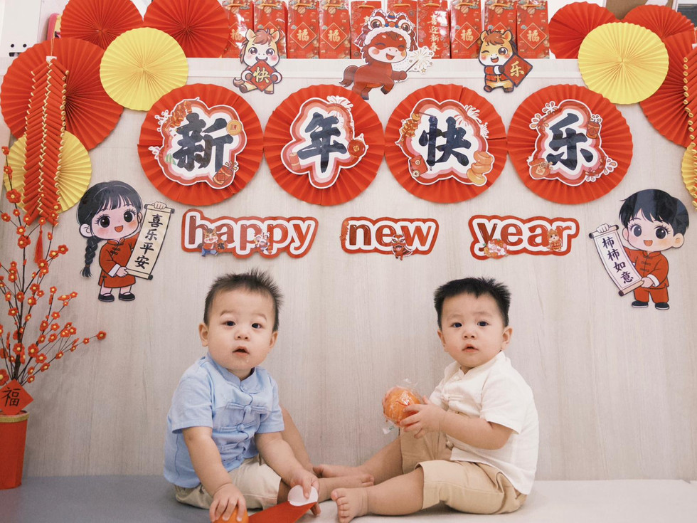 Two toddlers celebrating Chinese New Year with festive decorations.