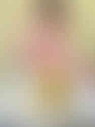 A baby focuses while placing sticks into a jar.