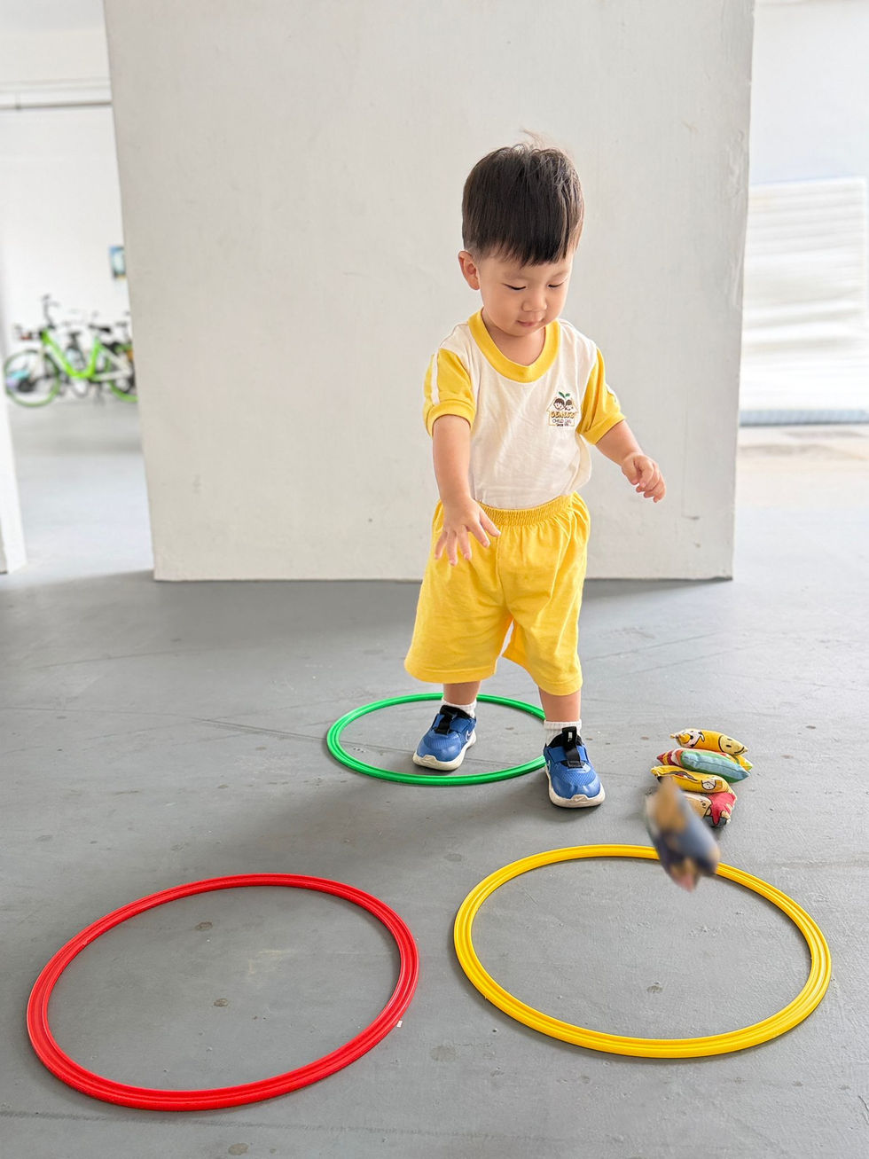 A toddler playing with colorful hoops and bean bags.
