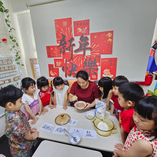 A teacher guiding children in making dumplings for a Chinese New Year celebration.