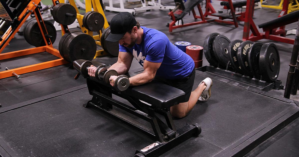 Man kneeling down and doing dumbbell wrist curls