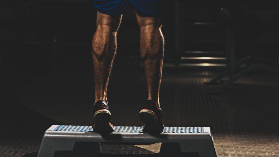 Man doing calf raises on box gym exercise