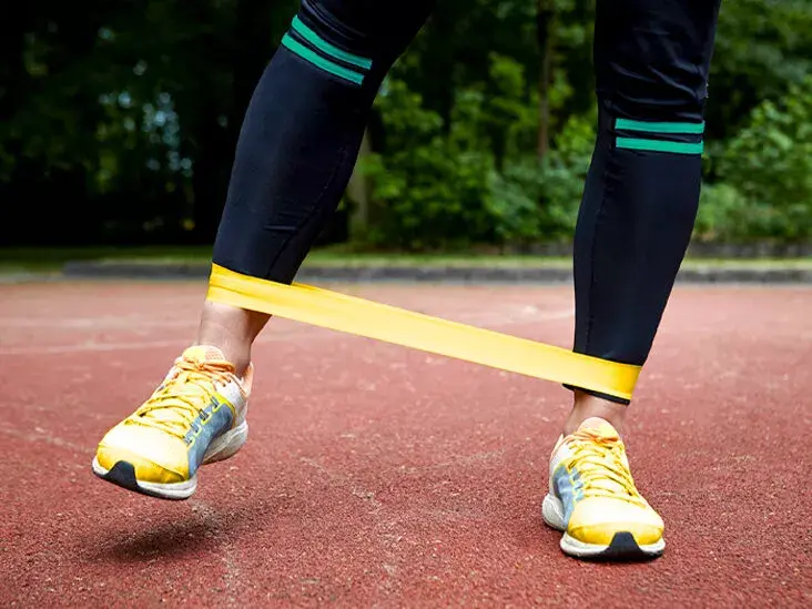 Man doing standing adduction with resistance bands to train his adductors
