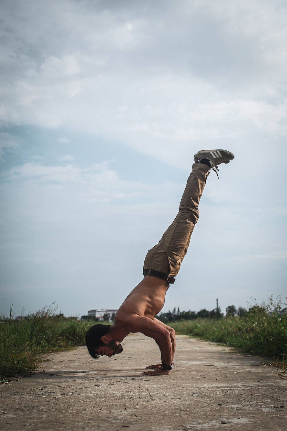 Shredded muscular shirtless male calisthenics athlete handstand push-ups outside on path