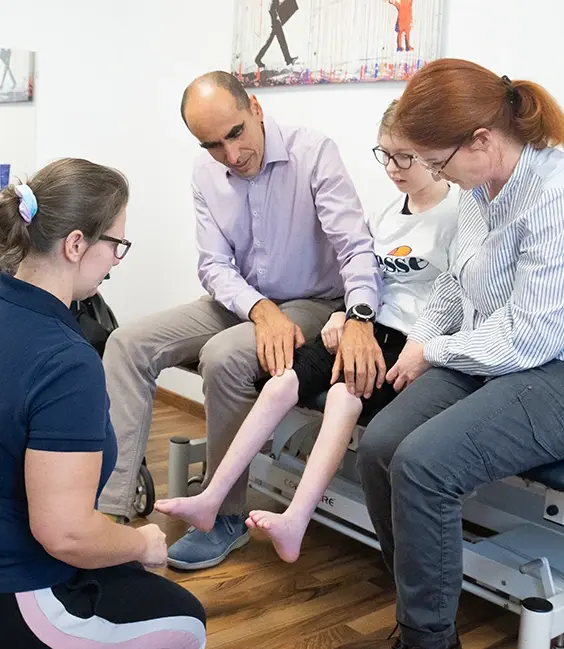Therapeut:in und Arzt besprechen Therapieplan fuer Kind mit Orthese